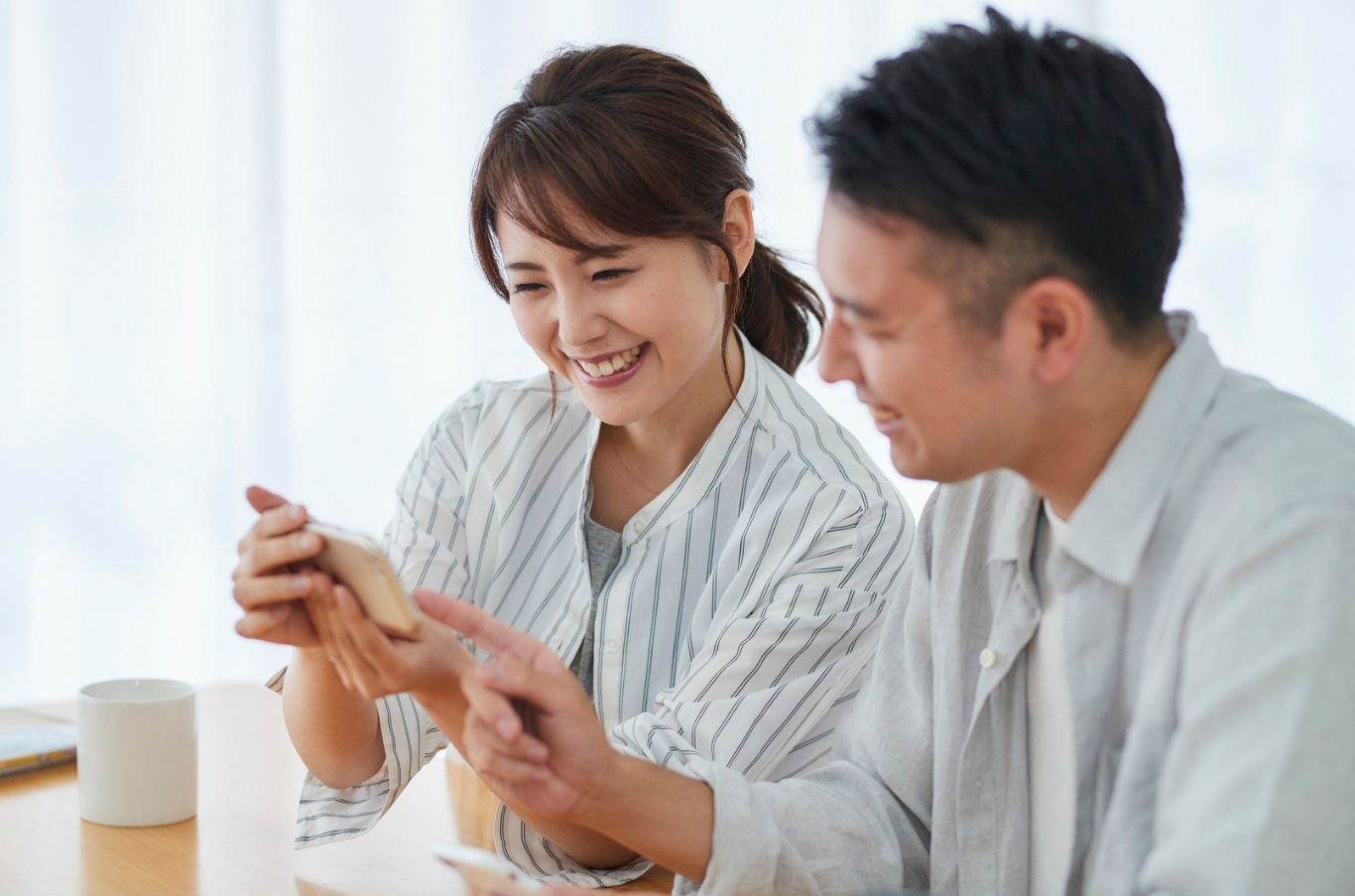 スマートフォンを見ながら笑顔で話すカップル